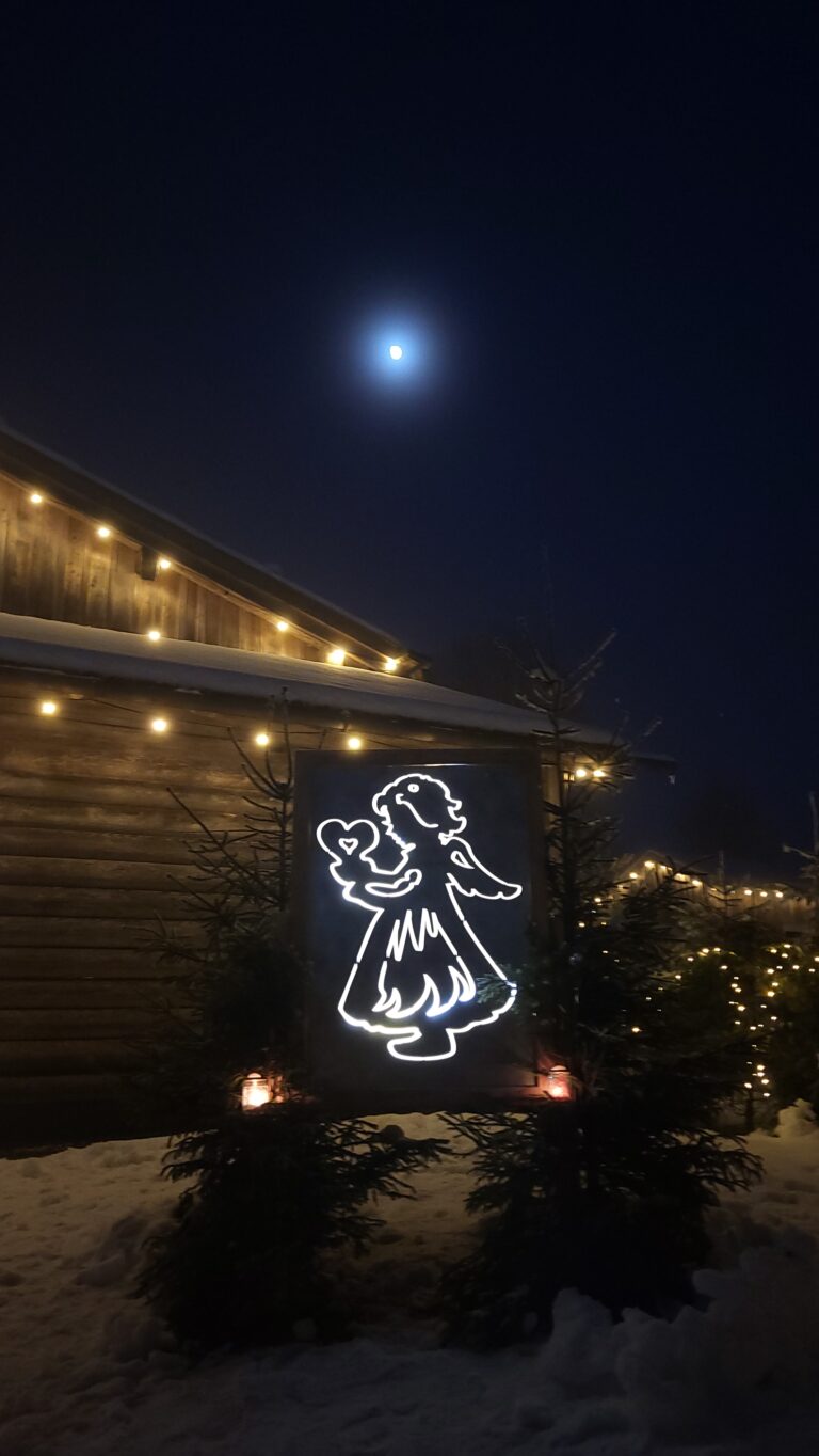 Schutzengel Lichtfigur vor einem Gebäude mit Mond im Hintergrund